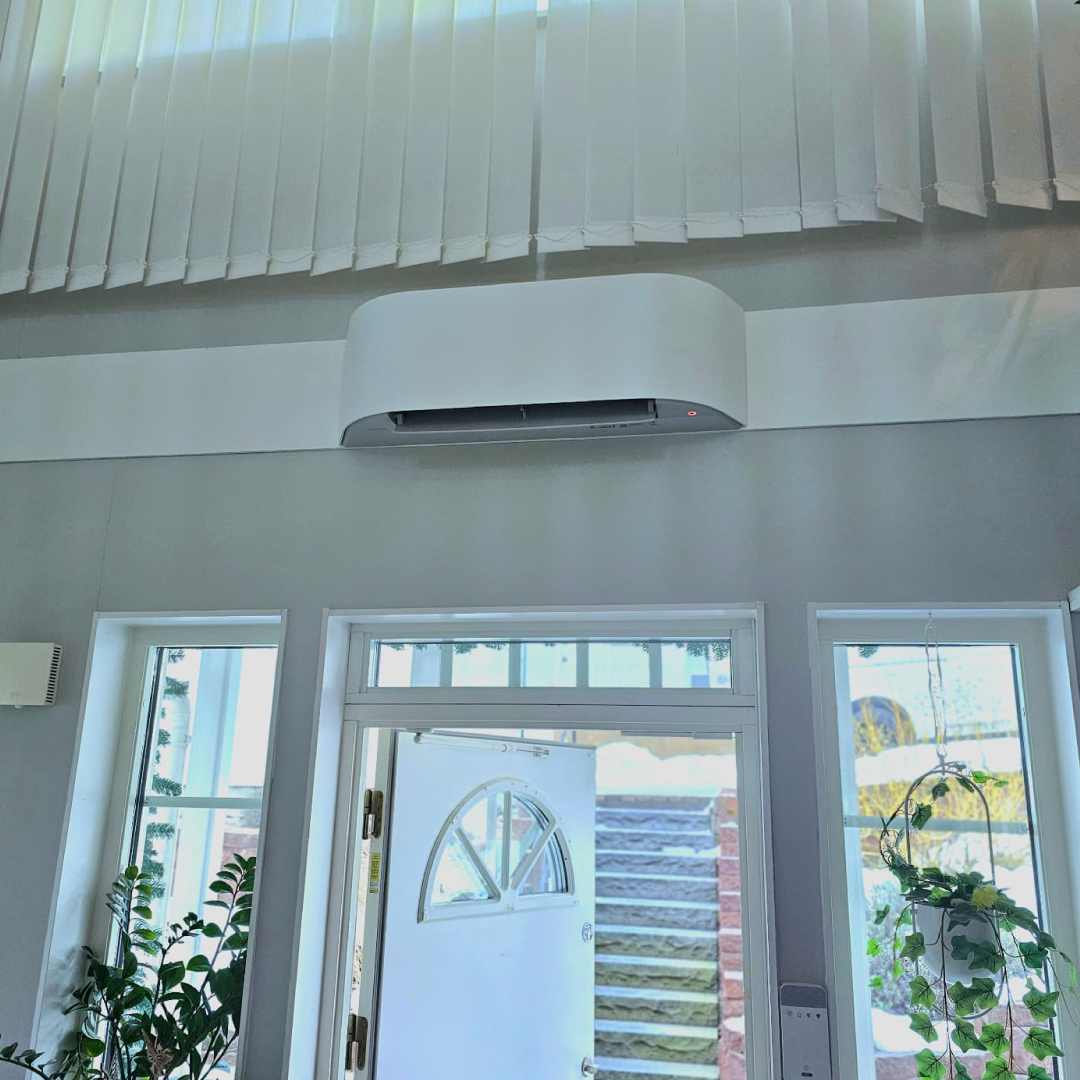 Toshiba HAORI med ljus textilfront, ovanför entrédörr. Installerad av oss i Nacka.